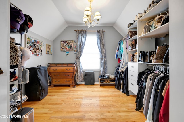 spacious closet featuring light wood-style floors, vaulted ceiling, and a chandelier