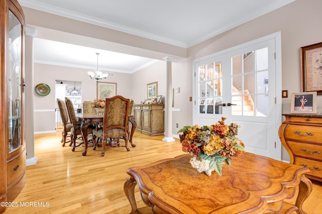 dining area with light wood finished floors, decorative columns, a chandelier, ornamental molding, and baseboards
