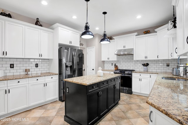 kitchen with stainless steel appliances, dark cabinets, under cabinet range hood, a sink, and white cabinetry