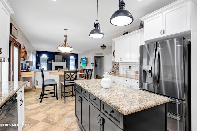 kitchen featuring stainless steel refrigerator with ice dispenser, white cabinets, backsplash, pendant lighting, and light stone countertops