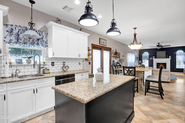 kitchen featuring a ceiling fan, decorative backsplash, a sink, white cabinetry, and dishwashing machine