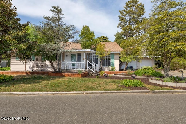 view of front of home with a porch, a front yard, and a garage