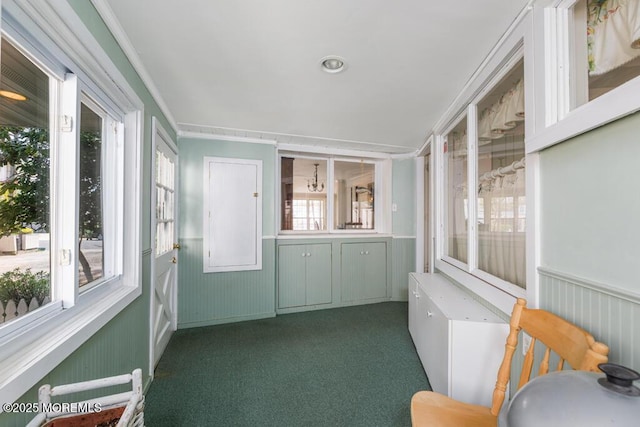 unfurnished sunroom featuring carpet floors, wainscoting, and a decorative wall