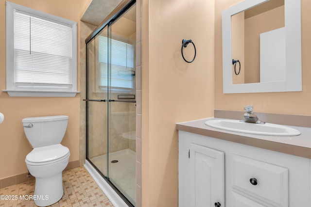 bathroom featuring a shower stall, toilet, vanity, and healthy amount of natural light
