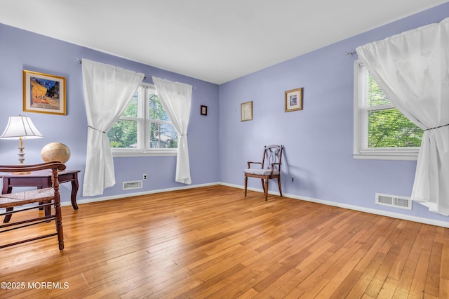 living area with healthy amount of natural light, light wood-style floors, and baseboards