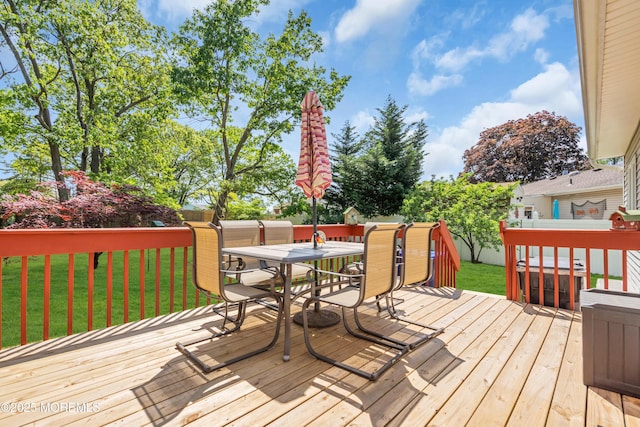 deck featuring outdoor dining area and a lawn