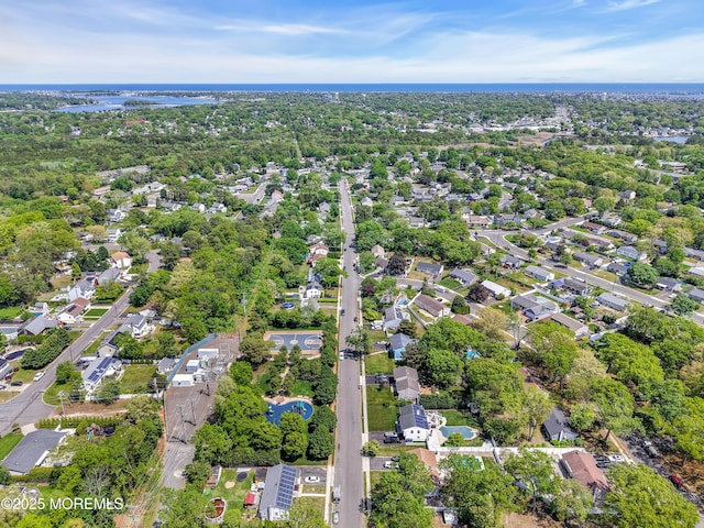 aerial view of property and surrounding area featuring a large body of water, nearby suburban area, and a tree filled landscape