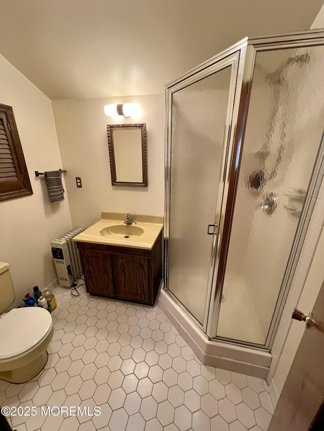 full bathroom with vanity, a shower stall, toilet, and radiator heating unit