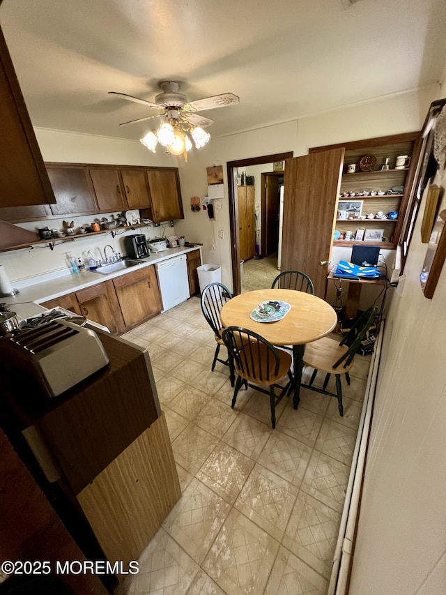 kitchen featuring light floors, dishwasher, light countertops, a sink, and a ceiling fan