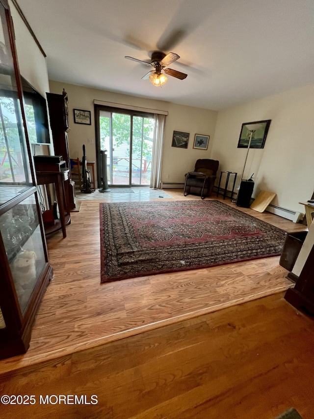 living room with a ceiling fan, light wood-style flooring, and a baseboard heating unit