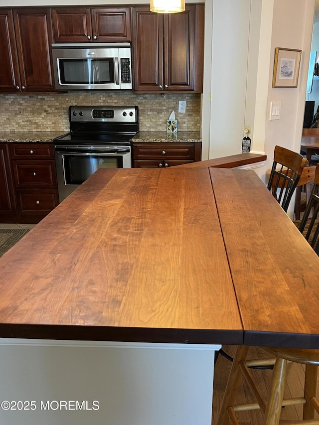 1 Channel Dr Unit 1203, Monmouth Beach, NJ 07750 - kitchen with stainless steel appliances, decorative backsplash, a center island, butcher block counters, and dark brown cabinets
