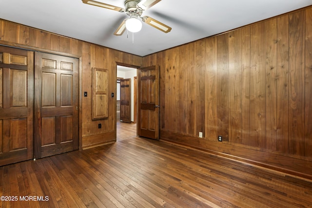 205 Edgemere Dr, Toms River, NJ 08755 - unfurnished bedroom with wood walls, dark wood-style flooring, a closet, and a ceiling fan