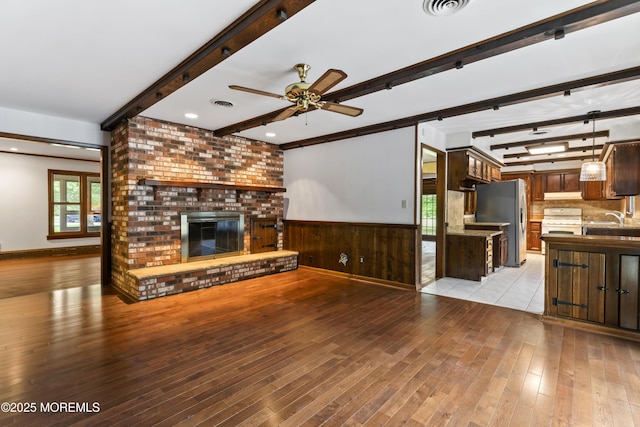 205 Edgemere Dr, Toms River, NJ 08755 - unfurnished living room with beamed ceiling, ceiling fan, light wood finished floors, a brick fireplace, and wainscoting