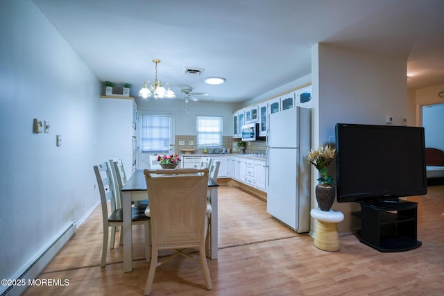 30F Cambridge Ct, Lakewood, NJ 08701 - dining space featuring a baseboard heating unit, light wood-style floors, a chandelier, and baseboards