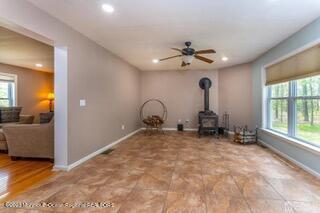 unfurnished living room with a wood stove, baseboards, recessed lighting, and ceiling fan