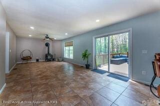 unfurnished living room with a wood stove, baseboards, ceiling fan, and recessed lighting