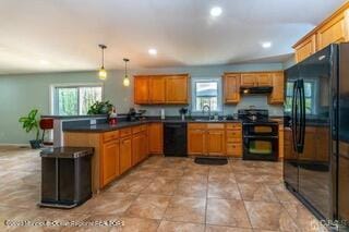 kitchen with black appliances, a peninsula, plenty of natural light, dark countertops, and recessed lighting