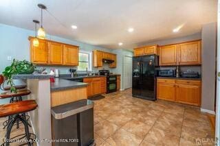 kitchen with black fridge with ice dispenser, stove, dark countertops, a peninsula, and a breakfast bar area