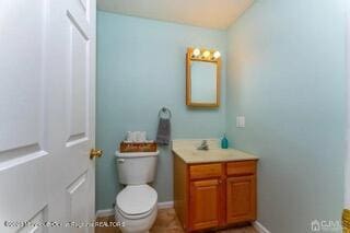 bathroom with toilet, baseboards, and vanity