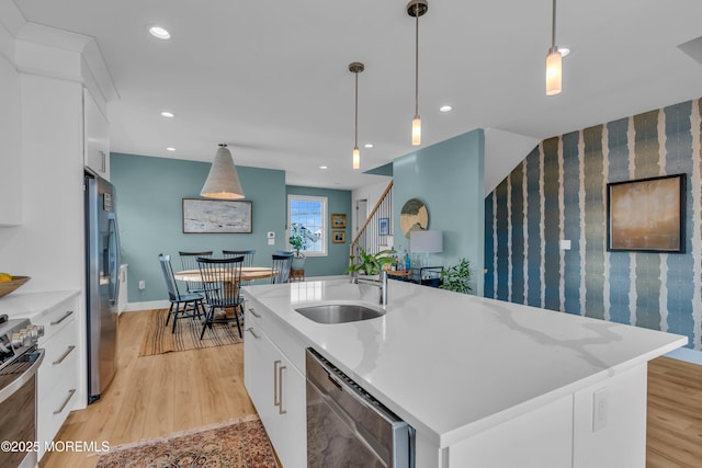 1709 Certainty Dr, Point Pleasant, NJ 08742 - kitchen with stainless steel appliances, a sink, white cabinetry, decorative light fixtures, and light wood-style flooring