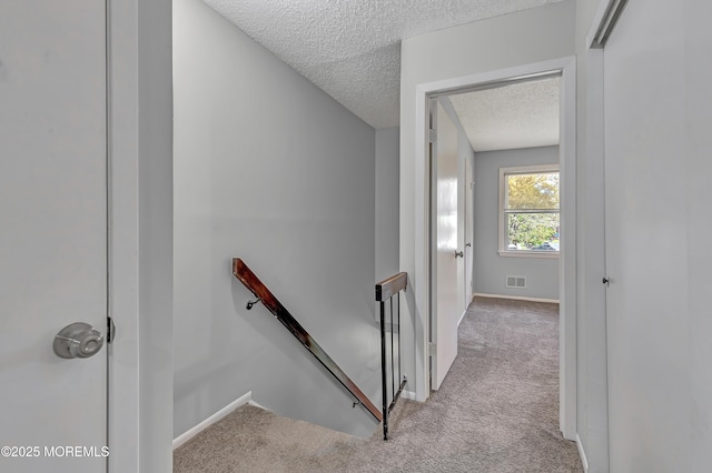 stairway with carpet flooring, a textured ceiling, and baseboards