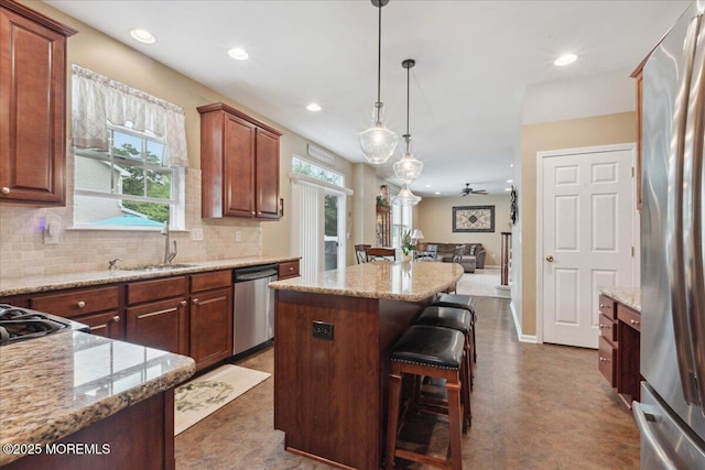 kitchen with appliances with stainless steel finishes, open floor plan, decorative backsplash, a center island, and a breakfast bar
