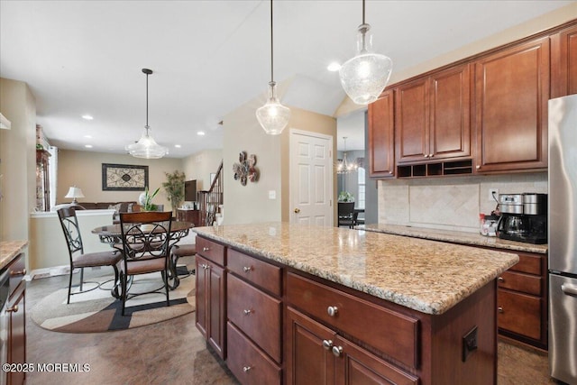kitchen with freestanding refrigerator, decorative backsplash, a center island, pendant lighting, and light stone counters