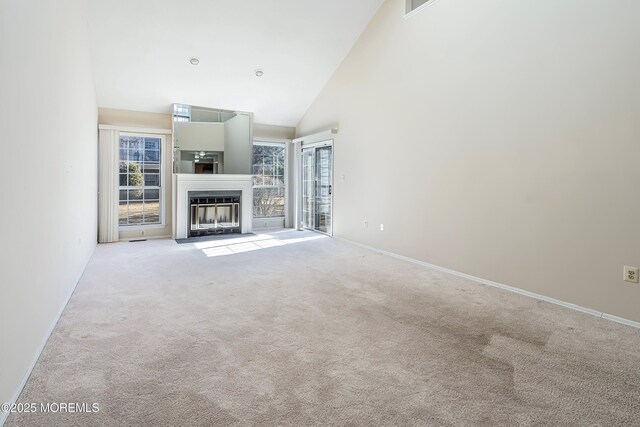 36C Canterbury Dr, Monroe, NJ 08831 - unfurnished living room with light colored carpet, high vaulted ceiling, plenty of natural light, and a fireplace with flush hearth