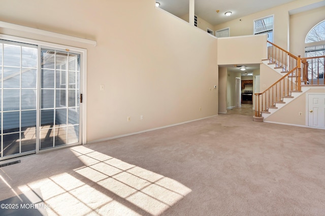 36C Canterbury Dr, Monroe, NJ 08831 - unfurnished living room with carpet floors, stairs, a towering ceiling, and baseboards
