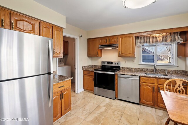36C Canterbury Dr, Monroe, NJ 08831 - kitchen with stainless steel appliances, a sink, under cabinet range hood, brown cabinets, and washer / dryer