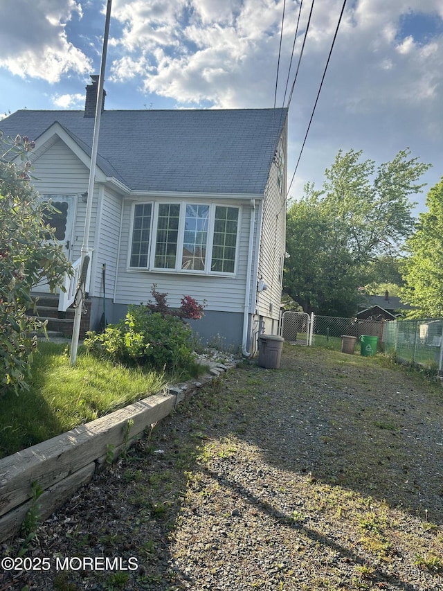 view of side of home with a chimney and fence