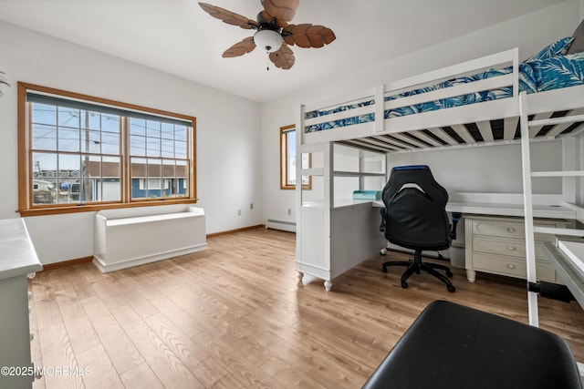 bedroom featuring multiple windows, wood finished floors, an office area, and baseboards