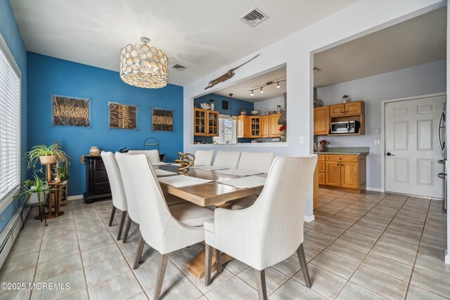 dining area with track lighting, a chandelier, light tile patterned floors, and baseboards