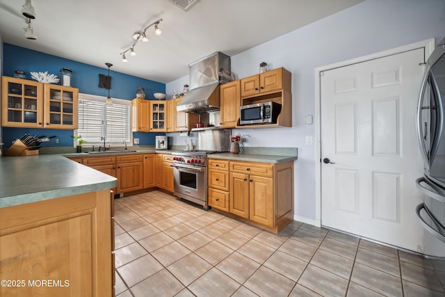 kitchen featuring stainless steel appliances, wall chimney range hood, a sink, light tile patterned floors, and glass insert cabinets