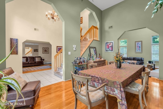 dining room with stairs, a high ceiling, wood finished floors, and a chandelier