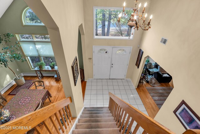 entryway featuring a high ceiling, a chandelier, wood finished floors, a baseboard radiator, and baseboards