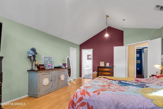 bedroom with light wood finished floors, high vaulted ceiling, ensuite bathroom, and baseboards