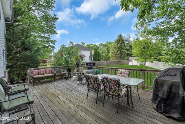 wooden deck featuring outdoor dining space, a shed, an outdoor structure, and grilling area