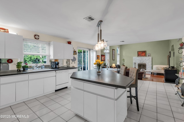 kitchen featuring white dishwasher, dark countertops, a sink, and a kitchen island