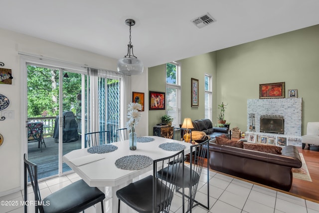 dining space featuring light tile patterned floors and a brick fireplace