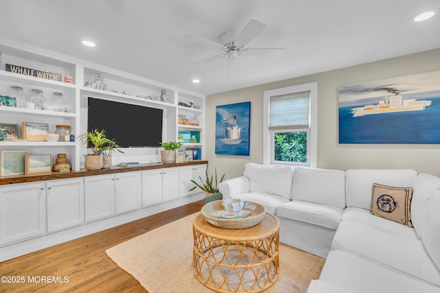 living room featuring light wood-type flooring, ceiling fan, recessed lighting, and built in shelves