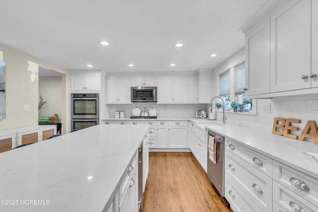 kitchen with appliances with stainless steel finishes, a sink, white cabinetry, tasteful backsplash, and recessed lighting