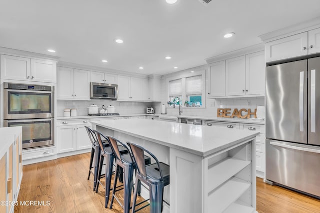 kitchen featuring stainless steel appliances, open shelves, a center island, white cabinets, and light wood finished floors