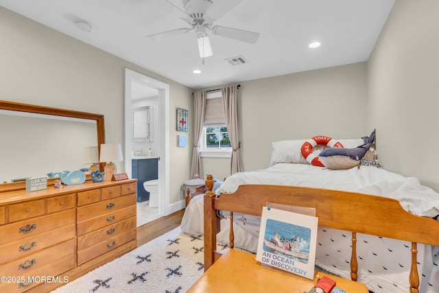 bedroom featuring wood finished floors, recessed lighting, ensuite bath, baseboards, and a ceiling fan