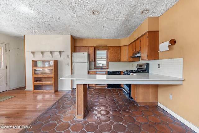 14 E Ave, Atlantic Highlands, NJ 07716 - kitchen featuring freestanding refrigerator, under cabinet range hood, stainless steel gas stove, brown cabinets, and a textured ceiling