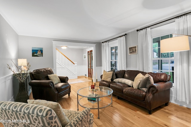living room with light wood-style flooring, stairway, a wainscoted wall, and crown molding
