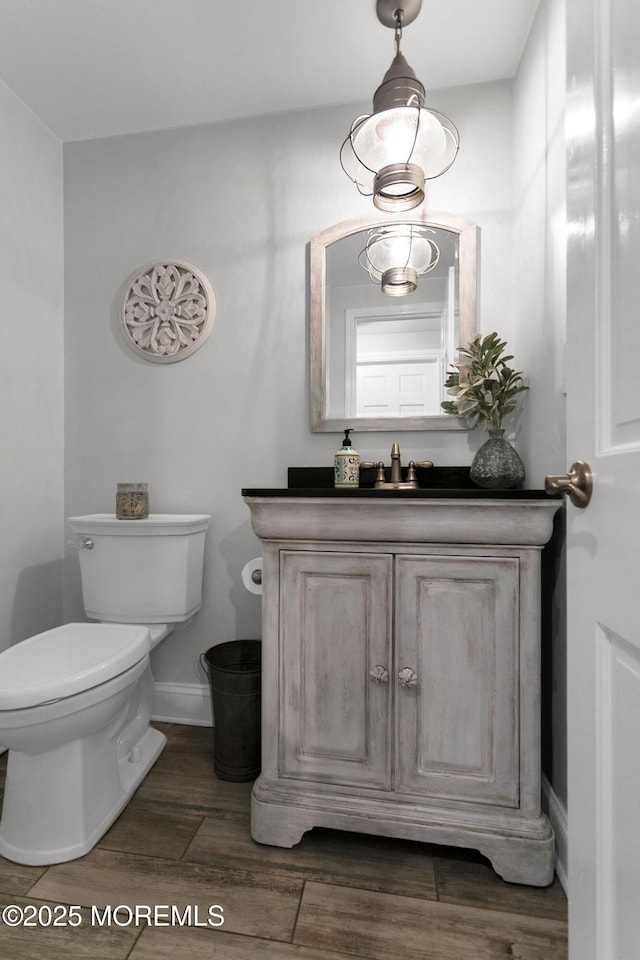 bathroom featuring toilet, vanity, wood finished floors, and baseboards