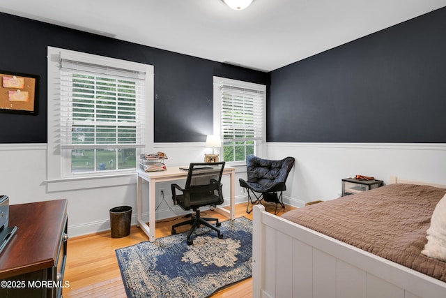 bedroom featuring wainscoting, light wood-style floors, and an office area