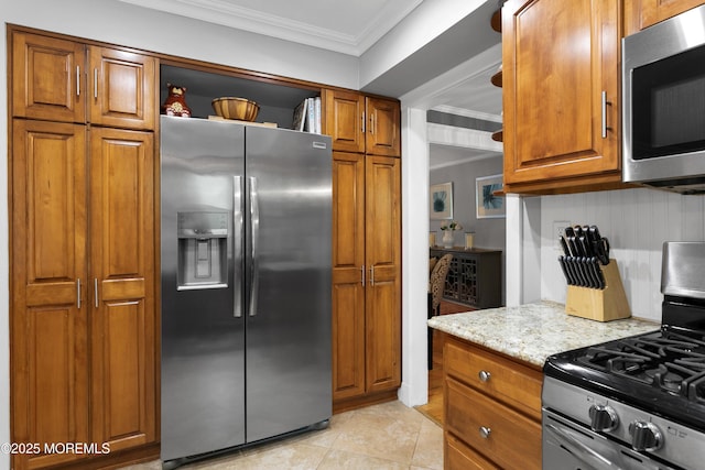kitchen featuring appliances with stainless steel finishes, brown cabinetry, ornamental molding, light stone counters, and light tile patterned flooring