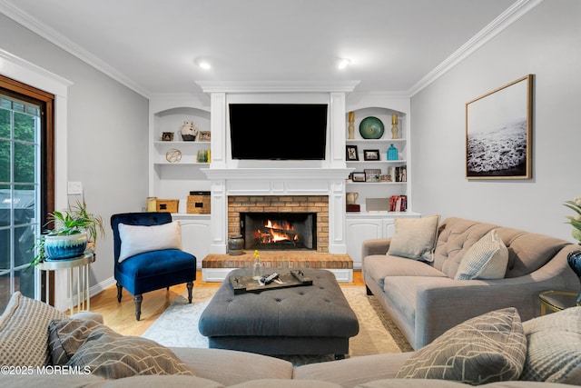 living room with ornamental molding, wood finished floors, built in shelves, a brick fireplace, and baseboards